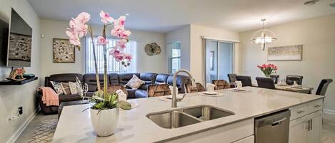 A modern kitchen with a large island, stainless steel appliances, and a dining area with a sofa and chairs.