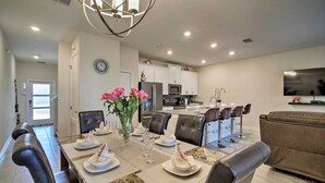 A modern dining area with a large table set for six, surrounded by leather chairs.