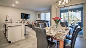 A modern kitchen with a dining area, featuring a large island, dark leather chairs, and a chandelier.