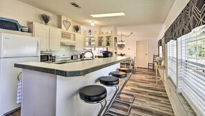 A modern kitchen with a central island, bar stools, and a view of the dining area. - 2 Living Rooms: Crescent City Home (Crescent City)