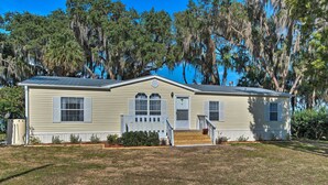 A single-story house with a front porch, a small front yard, and a large tree with Spanish moss. - 2 Living Rooms: Crescent City Home (Crescent City)