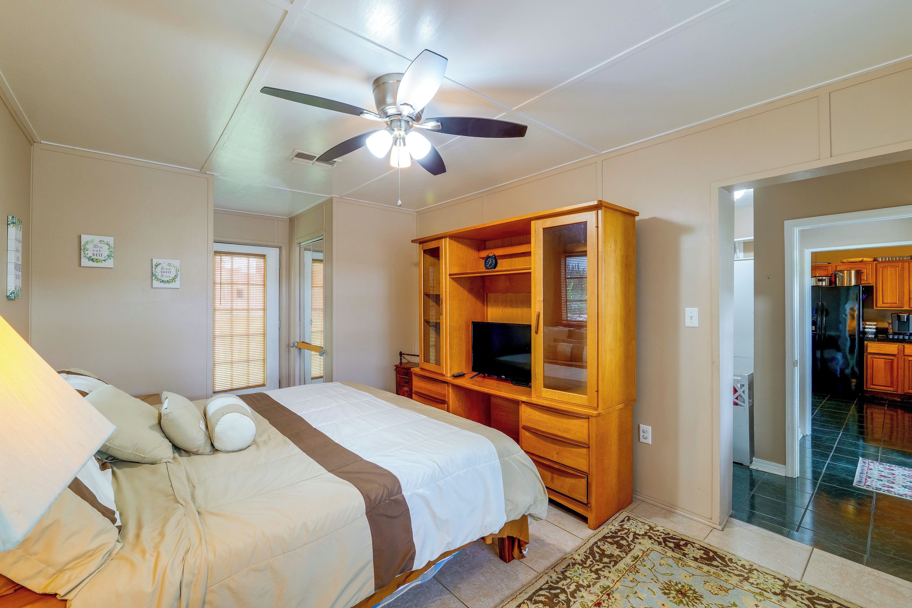 Une chambre à coucher avec un lit, un ventilateur de plafond, une télévision et une armoire en bois.