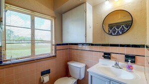A bathroom with a toilet, sink, and window with blinds. - Lakefront Retreat on Lake Ariana w/ EV Charger (Auburndale)