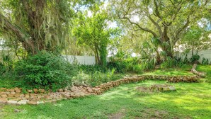 A garden with a stone pathway, lush greenery, and trees with hanging moss. - Lakefront Retreat on Lake Ariana w/ EV Charger (Auburndale)