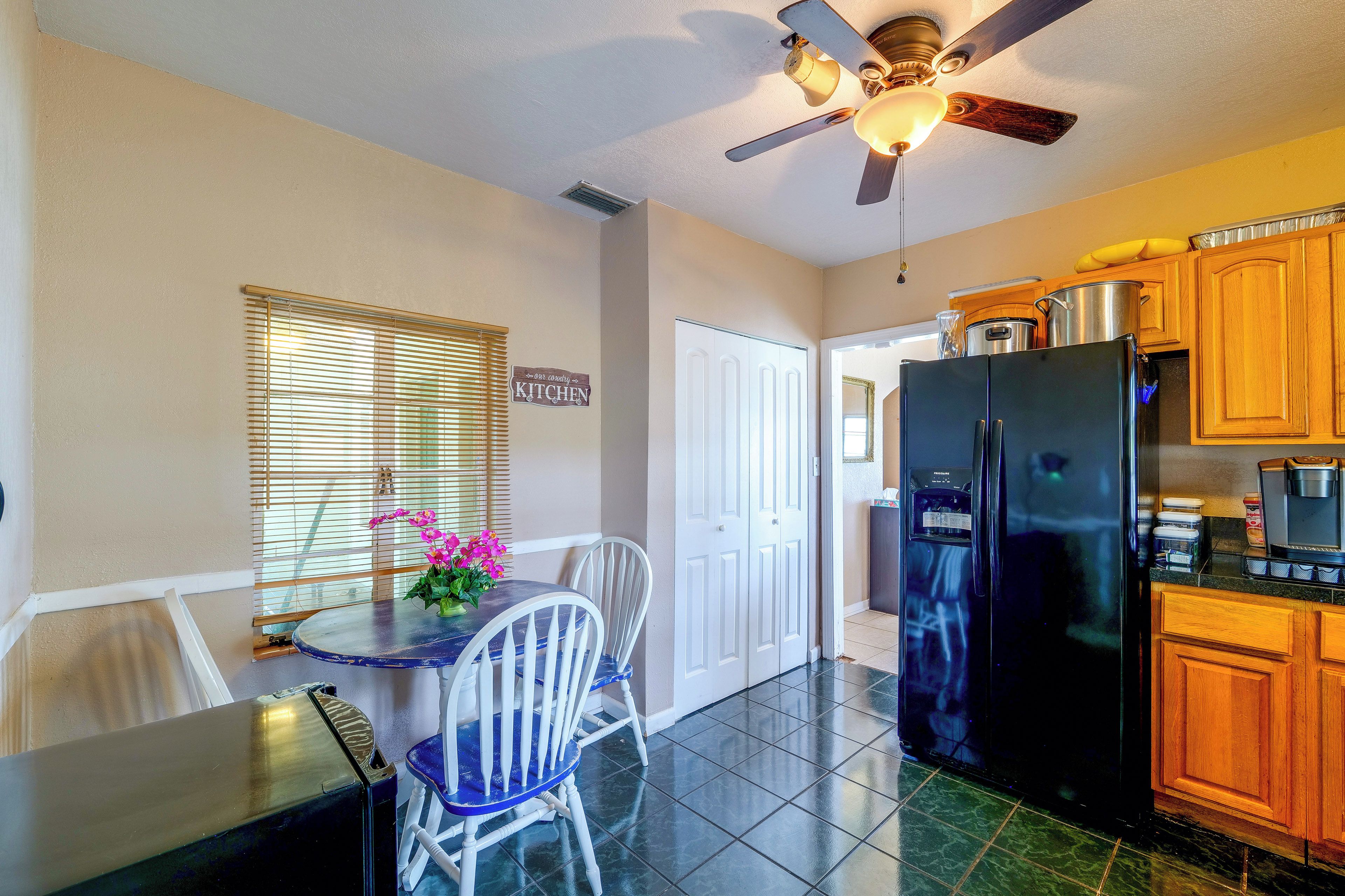 A kitchen with a refrigerator, stove, and a ceiling fan.