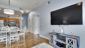 A modern kitchen with white cabinets, a microwave, and a dining area with a white table and chairs.