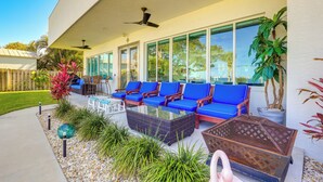 Eine Terrasse im Freien mit blauen, gepolsterten Sitzgelegenheiten, einem Tisch mit Glasplatte und Topfpflanzen.