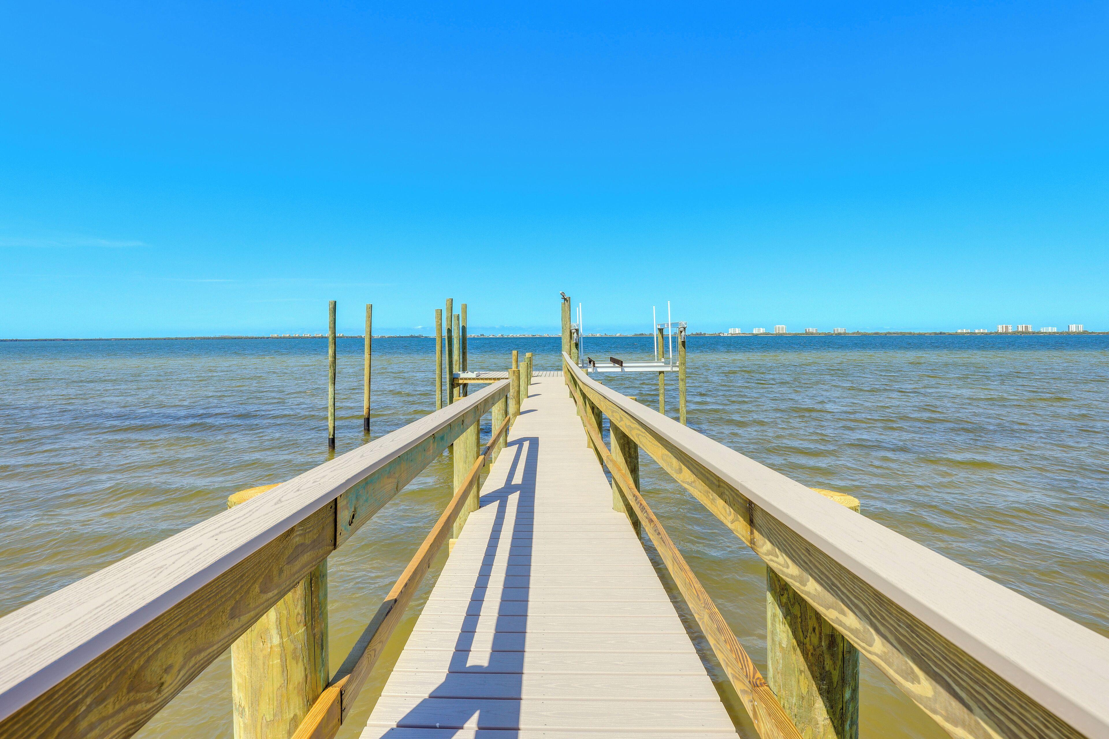 A wooden pier extending into calm waters with a clear sky above.
