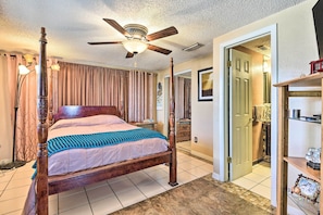 Classic four-poster bed and ceiling fan in a spacious room with a large window and comfortable seating area.