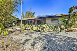 Surrounded by lush vegetation, this single-story house features a flat roof and a cozy front porch.