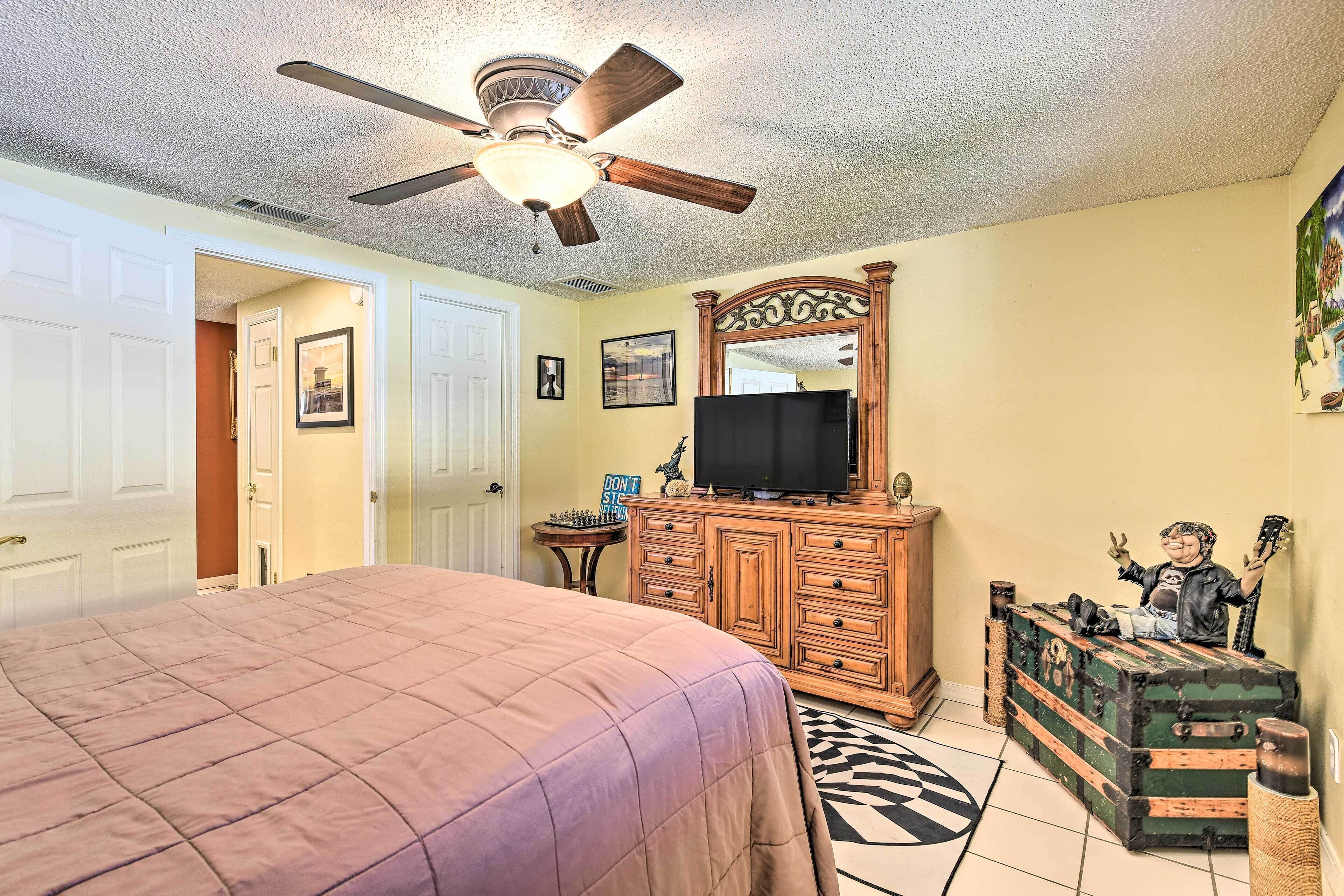 A bedroom with a bed, a dresser, a television, and a mirror.