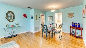 A dining area with a round table and chairs, a glass coffee table, and a wooden floor. - Walk to Beach: Fort Walton Coastal Retreat (Fort Walton Beach)