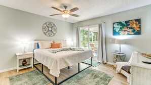 A bedroom with a bed, nightstand, lamp, and a painting on the wall. - Walk to Beach: Fort Walton Coastal Retreat (Fort Walton Beach)