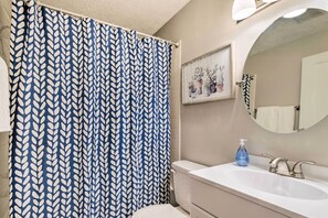 A bathroom with a white sink, a mirror, a blue and white patterned shower curtain, and a framed picture on the wall. - Cozy Ocala Home w/ Porch < 1 Mi to Downtown! (Ocala)