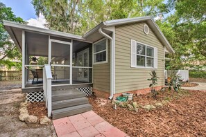 A single-story house with a covered porch, a small front yard with mulch and rocks, and a garden hose visible. - Cozy Ocala Home w/ Porch < 1 Mi to Downtown! (Ocala)