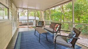 A covered porch with wicker furniture and a view of a vehicle in the background.