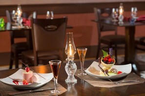 Savor fine dining in a sophisticated setting with a beautifully set table, complete with wine, champagne, and a decadent dessert.