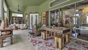 A spacious living area with a large glass door leading to a pool, a wooden coffee table, and a green sofa. - Luxurious Home w/ Private Pool & Lanai Near Tampa! (Odessa)