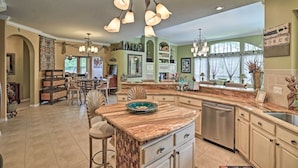 A spacious kitchen with a large island, a dining area with a chandelier, and a view of the outdoors. - Luxurious Home w/ Private Pool & Lanai Near Tampa! (Odessa)