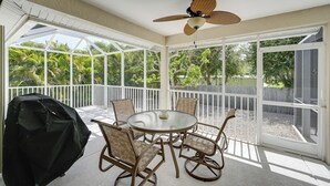 A covered patio with a round glass table and chairs, a ceiling fan, and a grill. - Sunny Marco Island House < 3 Blocks to Beach! (Marco Island)