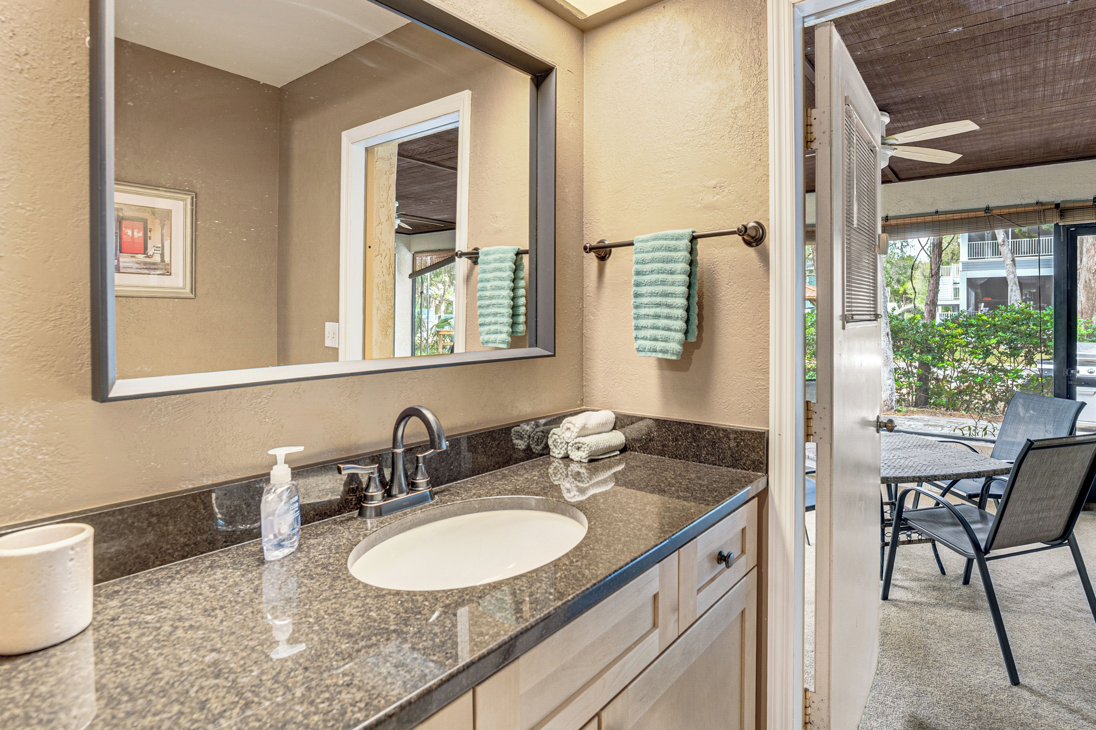 A bathroom with a large mirror, a sink, and a towel rack.