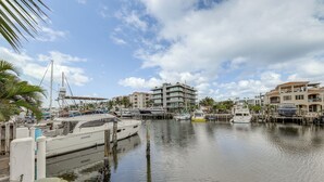 Ein Yachthafen mit mehreren angestuerten Booten, blauem Himmel und Gebäuden im Hintergrund.