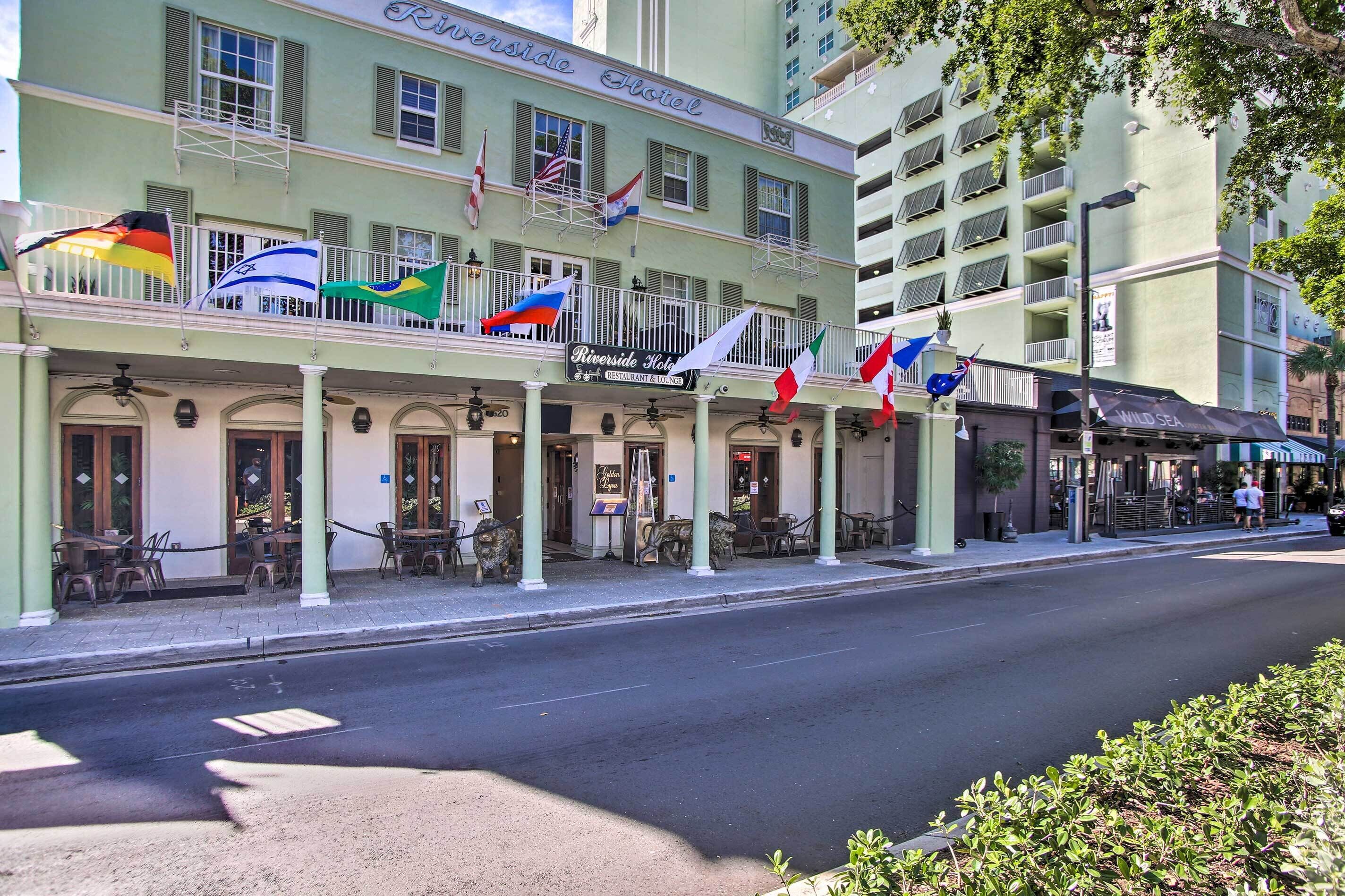 Un hôtel doté de nombreux balcons, de drapeaux et d’un espace extérieur aménagé pour s’asseoir.