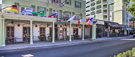 Un hôtel doté de nombreux balcons, de drapeaux et d’un espace extérieur aménagé pour s’asseoir.