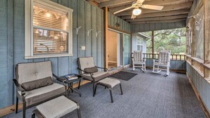 Ein gemütlicher Veranda-Bereich mit zwei Stühlen, einem Tisch, einem Deckenventilator und Blick ins Freie.