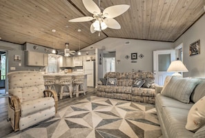 A spacious living room with a large ceiling fan, a patterned rug, and a sofa with cushions.