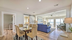 A spacious living area with a dining table and chairs, a blue sofa, and a view of the ocean. - Breezy PCB Retreat w/ Direct Beach Access! (Panama City Beach)