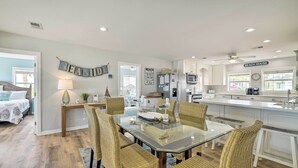 A modern kitchen with white cabinets, a glass dining table, wicker chairs, and a ceiling fan. - Breezy PCB Retreat w/ Direct Beach Access! (Panama City Beach)