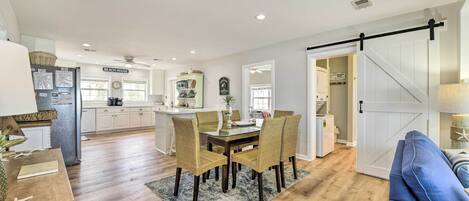 A spacious kitchen with a dining area, wooden flooring, and a sliding barn-style door.