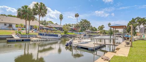 A marina with several boats docked, a covered area, and a grassy area with a pathway.