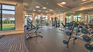 A spacious gym with various exercise equipment, large windows offering views of the outdoors, and a carpeted floor. - Lakewood National Condo w/ Pool Access! (Bradenton)