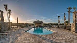 A pool area with lounge chairs, a small building, and palm trees. - Lakewood National Condo w/ Pool Access! (Bradenton)
