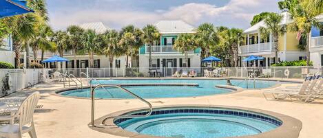 A pool area with multiple swimming pools, lounge chairs, and umbrellas.
