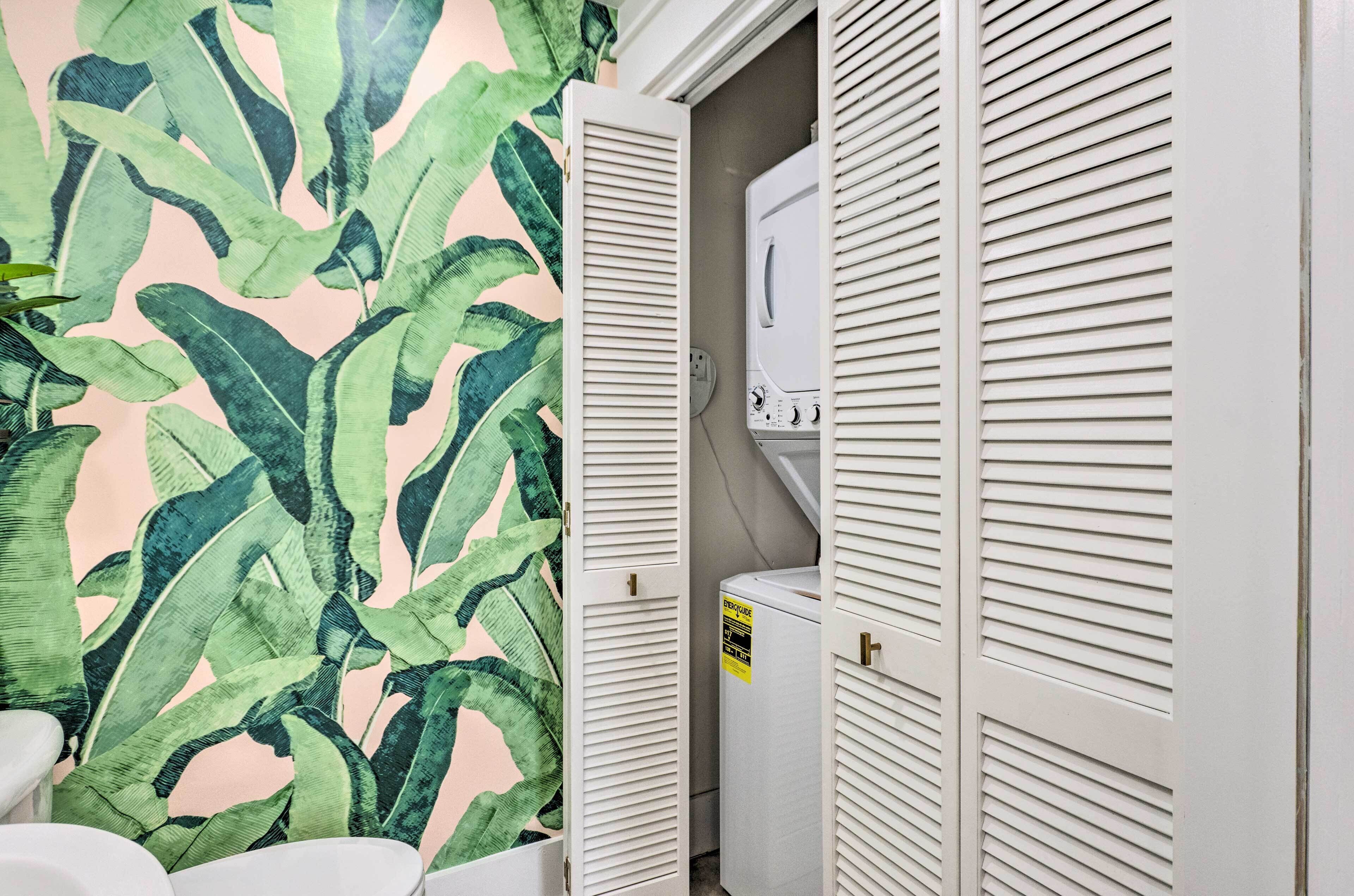 Ein Badezimmer mit Dusche, Toilette und einer Wand mit einem tropischen Blattmuster.