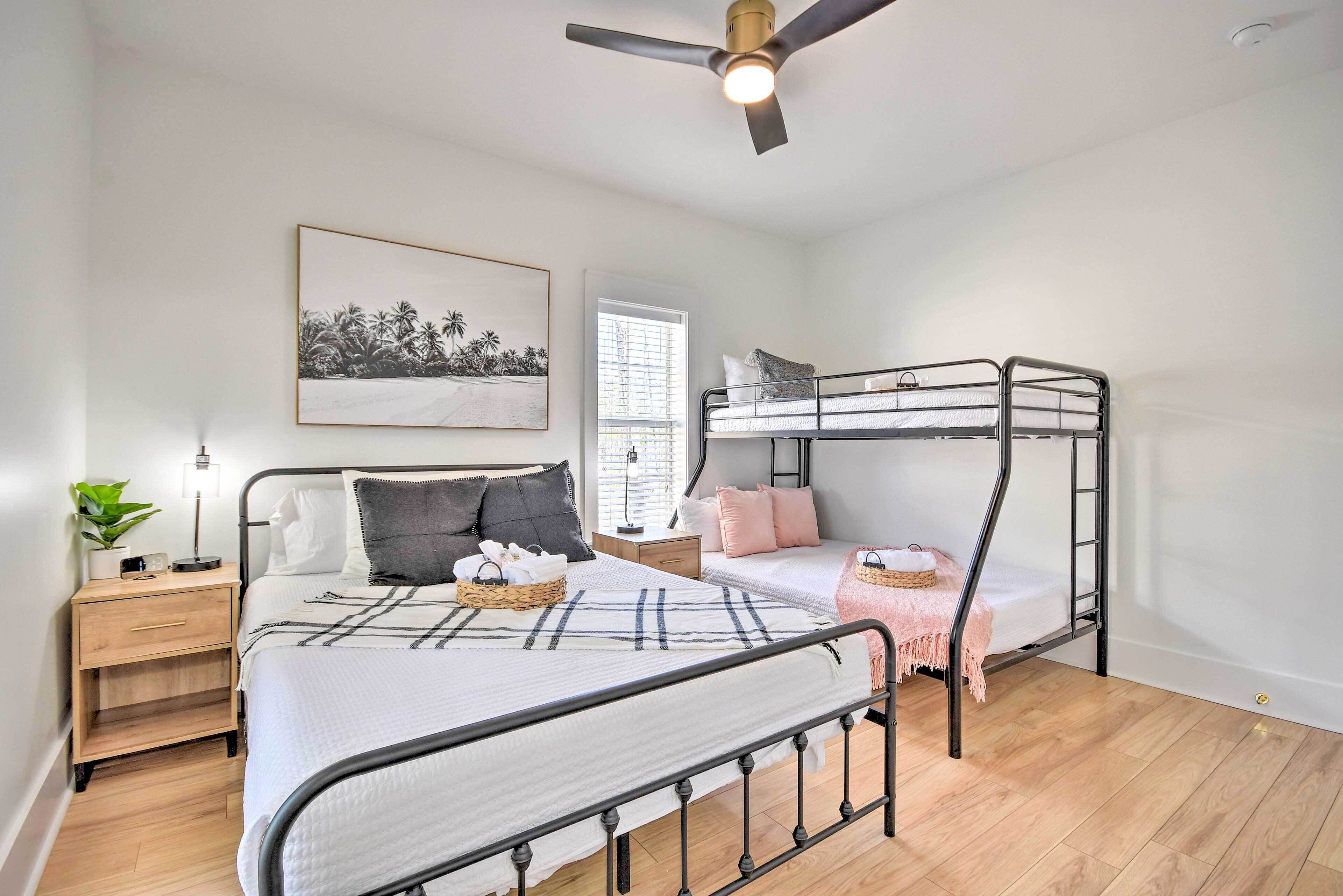 A bedroom with a bunk bed, a bedside table with a lamp, a framed picture on the wall, and a window with blinds.
