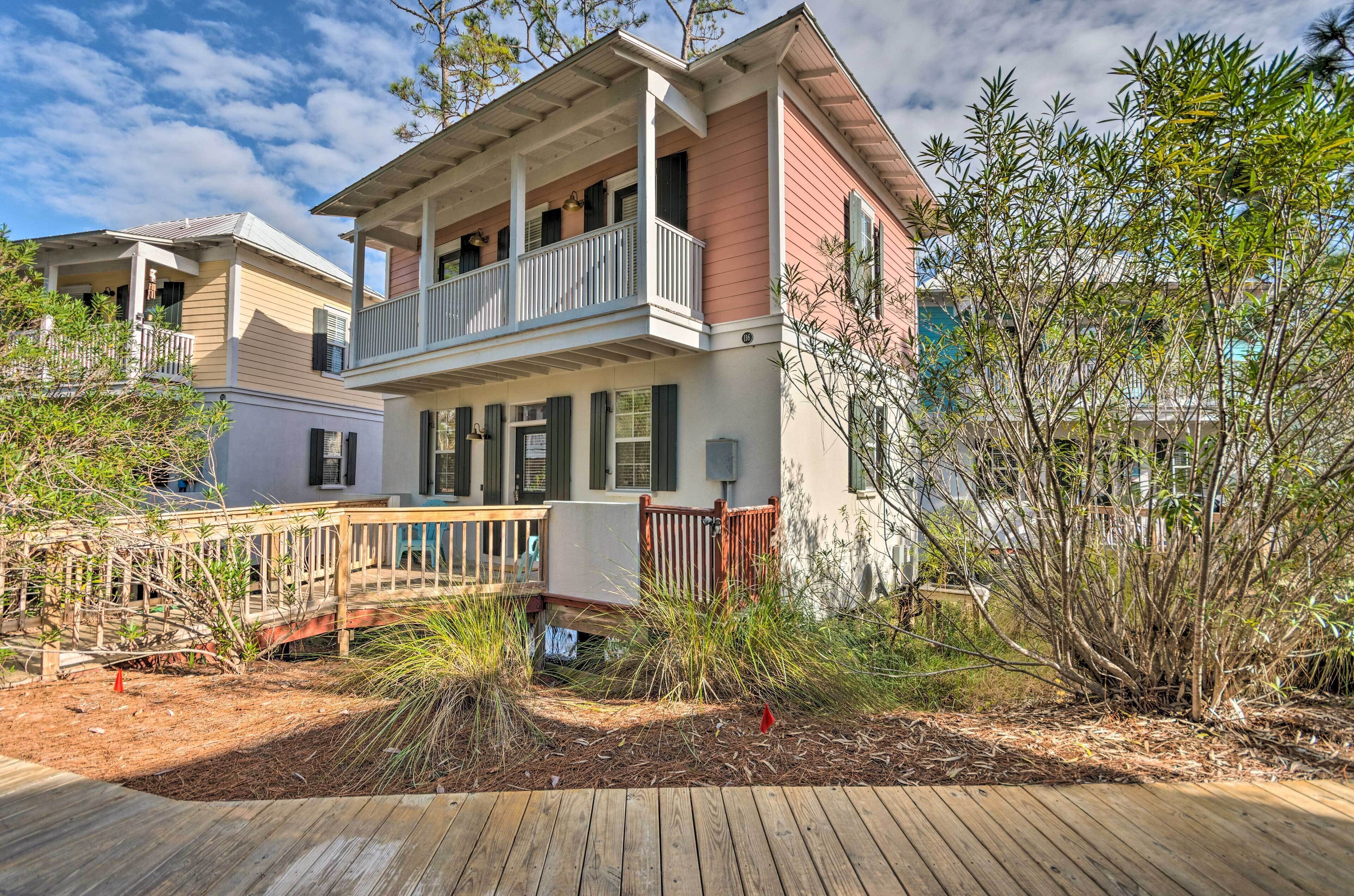 A two-story house with a balcony, a wooden deck, and a small bridge leading to the house.