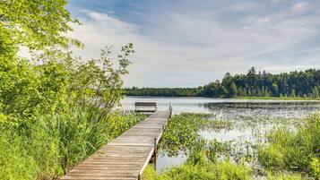 A wooden pier extending into a calm lake surrounded by lush greenery.