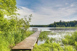 A wooden pier extending into a calm lake surrounded by lush greenery. - Dog-friendly Park Falls Cottage w/ 5 Acres & Lake (Park Falls)
