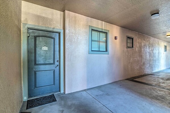 A hallway with a metal door, a window with blinds, and a textured wall. - Davenport Condo w/ Pool Access - 11 Mi to Disney! (Davenport)