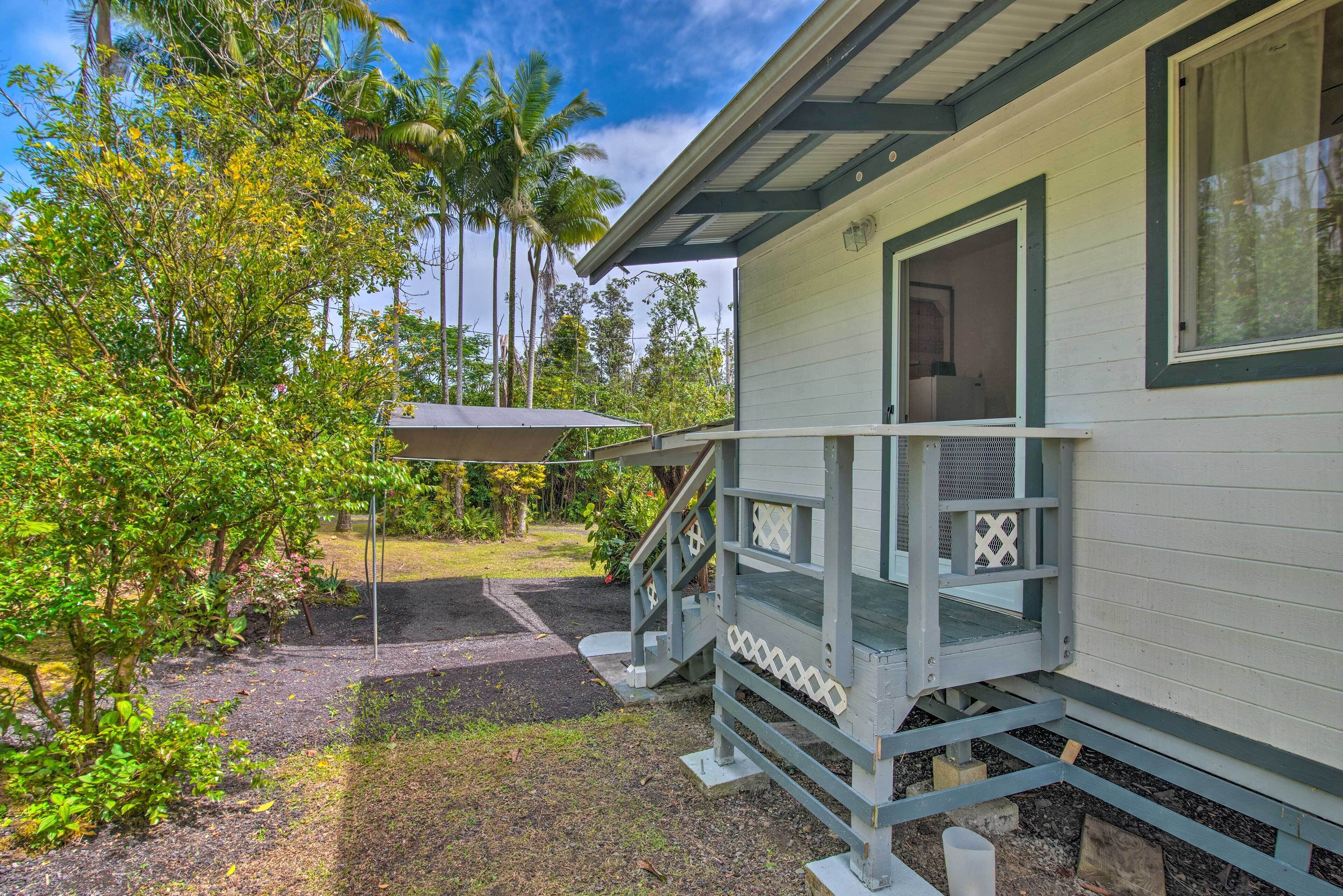 A house with a porch, a staircase, and a garden with trees and plants.