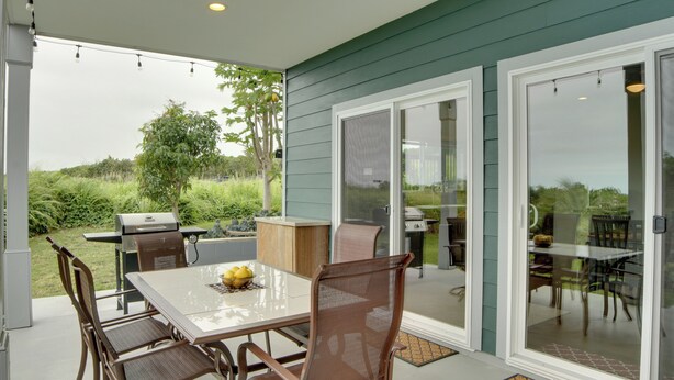 A covered patio with a dining table, chairs, and a grill. - Ocean Views Peaceful Retreat Volcano & Beaches (Naalehu)