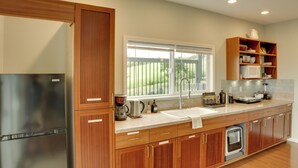 A modern kitchen with wooden cabinets, stainless steel appliances, a large window, and a built-in microwave shelf. - Ocean Views Peaceful Retreat Volcano & Beaches (Naalehu)