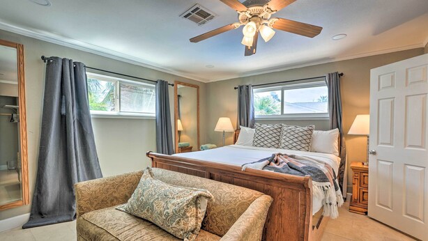 A bedroom with a bed, a wooden headboard, a ceiling fan, a window with curtains, a nightstand, and a patterned armchair. - Las Vegas Getaway w/ Patio & Grill: ~3mi to Strip! (Las Vegas)