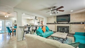 A modern living room with a fireplace, teal sofas, and a dining area with chairs and a table. - Las Vegas Getaway w/ Patio & Grill: ~3mi to Strip! (Las Vegas)