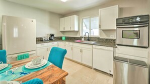 A modern kitchen with white cabinets, a stainless steel oven, and a dining area with a wooden table and blue chairs. - Las Vegas Getaway w/ Patio & Grill: ~3mi to Strip! (Las Vegas)