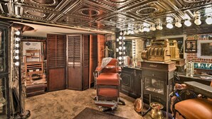 A vintage barber shop with ornate ceiling, a vintage barber chair, and a mirror with lights. - Historic Home < 2 Mi to Daytona Beach & Pier! (Daytona Beach)
